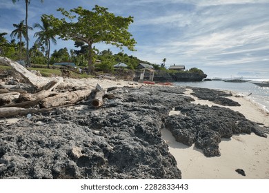 An idyllic, lonely beach of Pamilacan Island in the Philippines with rough rocks in the foreground and boats out on the water. - Shutterstock ID 2282833443