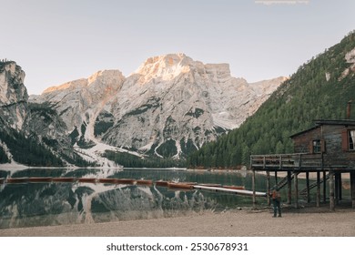 Idyllic mountain lake view with boats and rustic cabin in the Dolomites at sunrise - Powered by Shutterstock