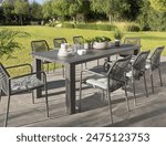 Idyllic outdoor dining set in a verdant garden, a sleek modern slate-gray aluminum table, stylish woven rope chairs with cushions, perfectly placed for a refreshing morning breakfast under the sun.