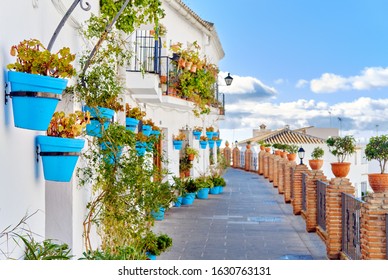Idyllic scenery empty picturesque street of small white-washed village of Mijas. Path way decorated with hanging plants in bright blue flowerpots, Costa del Sol, Andalusia, Province of Málaga, Spain
