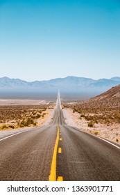 Idyllic vertical panorama view of an endless straight road running through the barren scenery of the American Southwest with extreme heat haze on a beautiful sunny day with blue sky in summer