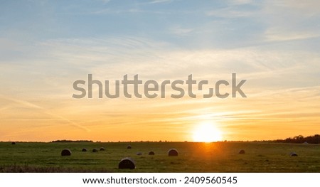 Idyllic view of field and straw rolls against sky during sunset, Lithuania, Europe.