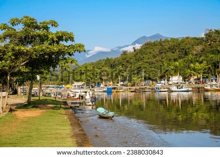 Idyllic view of river Perequê-Açu at lowe tide with colorful tour boats, trees and rainforest mounta