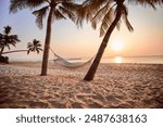 Idyllic wallpaper of a hammock on a tropical island among palm trees at sunset