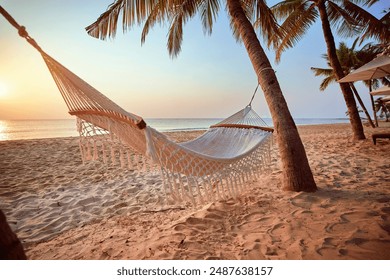 Idyllic wallpaper of a hammock on a tropical island among palm trees at sunset - Powered by Shutterstock