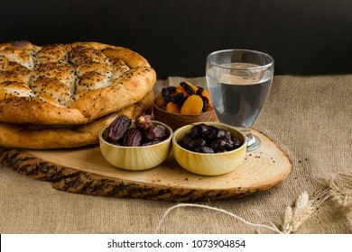 Iftar meal,time to break with sweet dry dates,apricot,black olives,water and Ramadan Bread on the wooden board.Beginning meal before main menu.