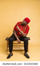 Igbo Traditionally Dressed Business Man Sitting Down and Point at Imaginary Product