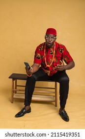 Igbo Traditionally Dressed Business Man Sitting Down and with Phone and jubilant