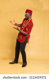 Igbo Traditionally Dressed Business Man Standing Highlighting a Product with Both Hands