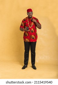 Igbo Traditionally Dressed Business Man Standing with Phone in Hand Looking