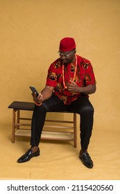 Igbo Traditionally Dressed Business Man Sitting Down and Staring at Phone in Shock