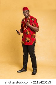 Igbo Traditionally Dressed Business Man Standing with Phone in Hand and smiling
