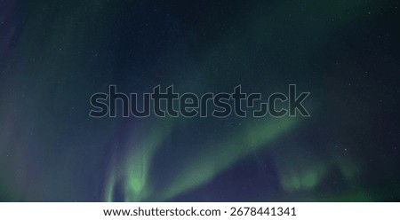 Igloo in winter forest against the backdrop of incredible starry sky with Aurora borealis. Northern lights in winter mountains. Wintry scene with glowing polar lights and icehouse. Christmas postcard