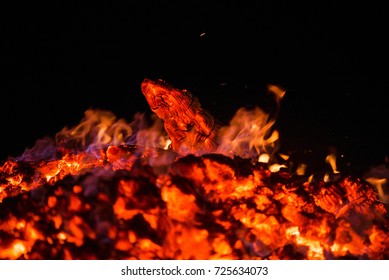 Ignite the fire. Warming up the cold winter nights. A macro shot of firewood and hot, glowing coal. Burning branches and wood. Flames in the fireplace, cozy home, warmth, love, romantic