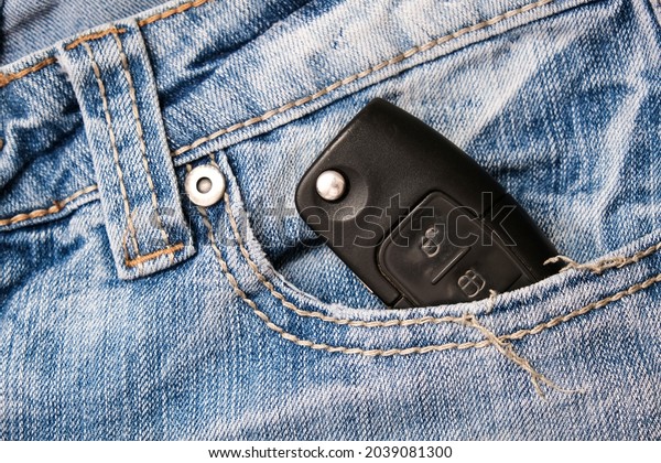 An ignition key for a car, auto in a\
jeans pocket, car security and protection\
concept