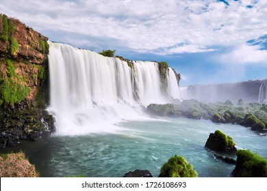 Iguazu waterfalls in Argentina, view from Devil's Mouth. Panoramic view of many majestic powerful water cascades with mist. Side view of the wide powerful waterfall. Turquoise water and stones. - Powered by Shutterstock