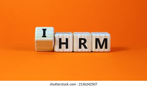 IHRM, International Human Resource Management HRM Symbol. Words IHRM, International Human Resource Management On Cubes On A Orange Background. Businessman Hand. Business, IHRM HRM Concept. Copy Space.