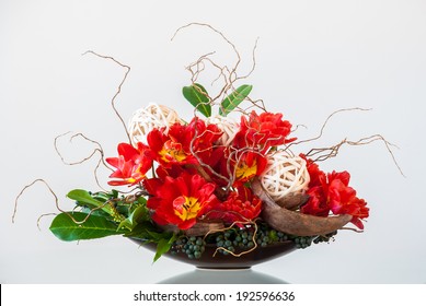 Ikebana-like Artistic Flower Arrangement In A Container On A Glossy Table