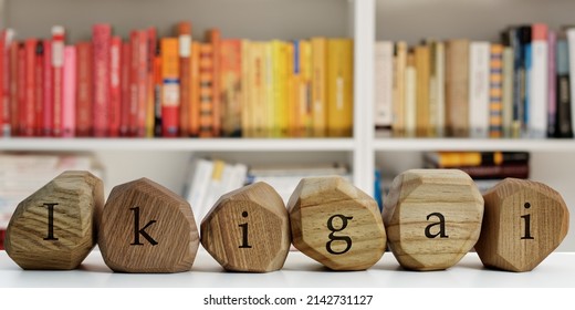 Ikigai Word (Japanese Word For Reason For Being) Written On Wooden Blocks. Blurred Books Behind. Life Meaning Concept.