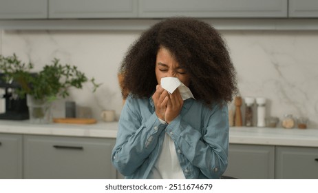 Ill allergic African American woman sneezing in tissue blowing running nose at home kitchen sick biracial girl suffer flu ethnic female lady suffering allergy symptoms unhealthy seasonal virus disease - Powered by Shutterstock