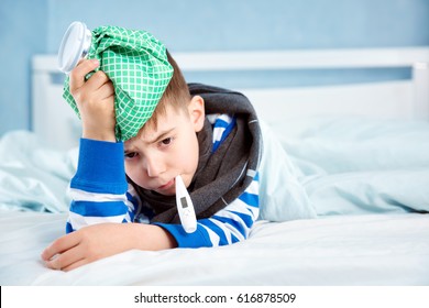 Ill Boy Lying In Bed. Sad Child With Fever And Ice Bag On Head