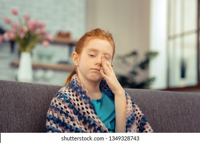 Ill Child. Cheerless Pale Girl Rubbing Her Face While Feeling Ill