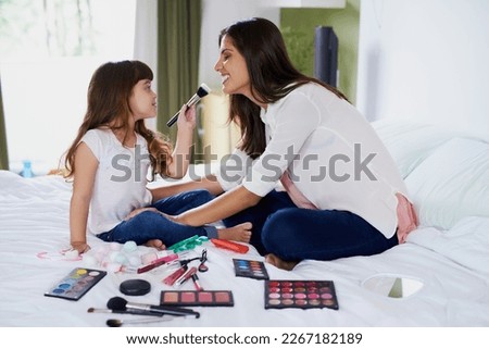 Ill give you the best makeover, Mom. Shot of a mother and her little daughter playing with makeup on the bed at home.