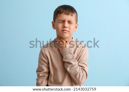 Ill little boy with sore throat on color background