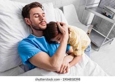 ill man embracing daughter while lying in hospital bed - Powered by Shutterstock