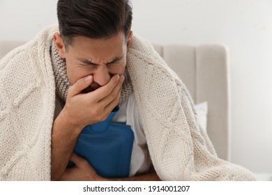 Ill Man With Hot Water Bottle Coughing At Home