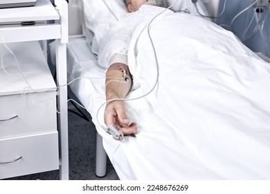 ill senior male patient in hospital bed. Healthcare and treatments concept. mature man recovering after Covid 19, coronavirus. man is injected, lies with a dropper in modern hospital. close-up hands - Powered by Shutterstock