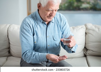 Ill Senior Man Taking Pill And Drinking Water