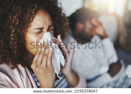 Ill or sick woman with allergy, sinus infection sneezing in tissue or blowing nose during flu season at home. Sick girl caught a bad cold showing symptoms of covid, or suffering from a virus disease