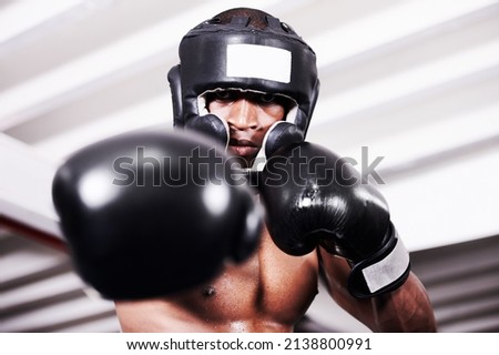 Ill take you one. An african american boxer wearing protective gear standing in the ring.