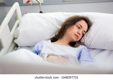 Ill  tired female is lying unhappy on bed in hospital. - Shutterstock ID 1048397731