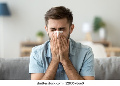 Ill young man sneezing in handkerchief blowing wiping running nose, sick allergic guy caught cold got flu influenza hay fever coughing, having seasonal allergy symptoms respiratory contagious disease - Shutterstock ID 1283698660