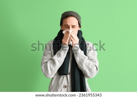 Ill young man with tissue on green background