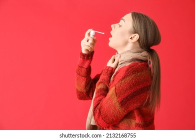 Ill Young Woman With Sore Throat Using Inhaler On Red Background