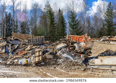 Illegal dump in the woods. Environmental pollution from construction waste. Negative impact on nature. Construction debris has accumulated in the forest. Garbage dump on the grass near the road