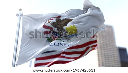 The Illinois state flag flapping in the wind with the American national flag blurred in the background. Democracy and independence. American midwest state.