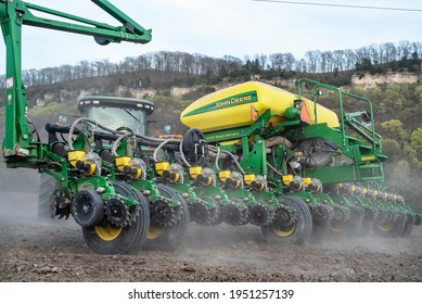 Illinois, USA, April 6 2021 - Farmer On Tractor Pulling John Deere Seed Planter In Corn Field Planting In Spring. Spreading, Plant, Sowing Seeds, Hoppers, Precision, Mechanical Machinery, Grow