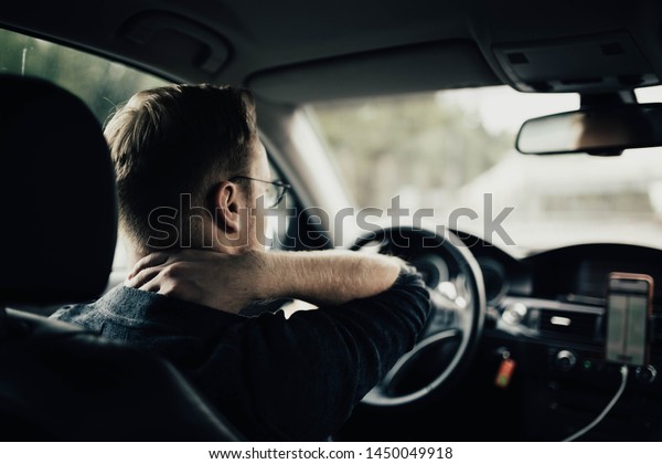 illness of the back and\
neck of the driver. A tired auto driver is massaging his neck on a\
trip.
