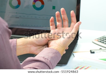Illness hand. Portrait of a businessman with a beard while working in his office, holding hand