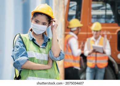 Illness Manufacture Worker Woman With Mask Cover Face Stands N Front Of Workers Inspecting And Meeting At Heavy Machine Vehicle Car. Smart Woman Working On Site Of Industry Factory.