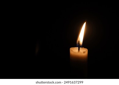 Illuminate the darkness with a flickering candle, casting a warm glow against a dark backdrop, creating a captivating ambiance. - Powered by Shutterstock