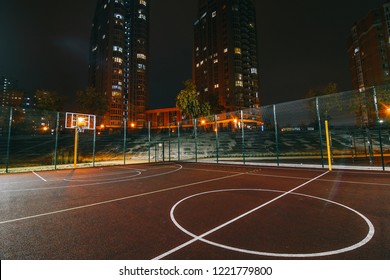 Illuminated basketball playground with red pavement, modern new basketball net and lens flares on background. 