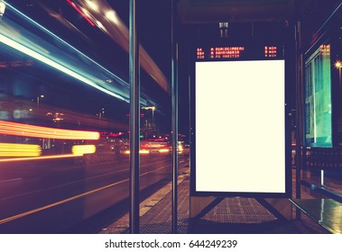 Illuminated blank billboard with copy space for your text message or content, advertising mock up banner of bus station, public information board with blurred vehicles in high speed in night city - Shutterstock ID 644249239