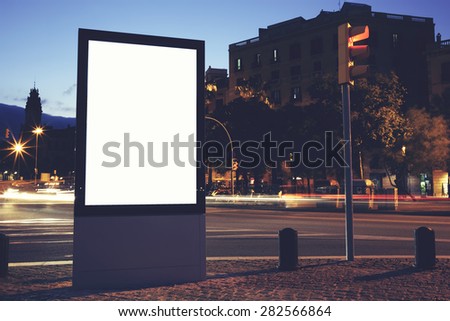 Illuminated blank billboard with copy space for your text message or content, public information board in night city with beautiful dusk on background, advertising mock up banner in metropolitan city