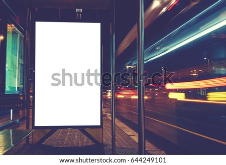 Illuminated blank billboard with copy space for your text message or content, advertising mock up banner of bus station, public information board with blurred vehicles in high speed in night city