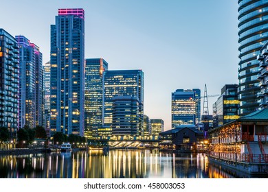 Illuminated Buildings In Canary Wharf, London Seen From Millwall Dock